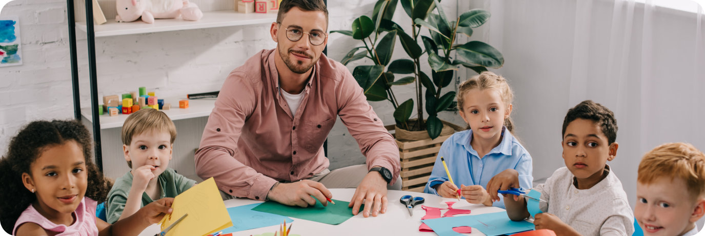 Male teacher and young students doing paper crafts
